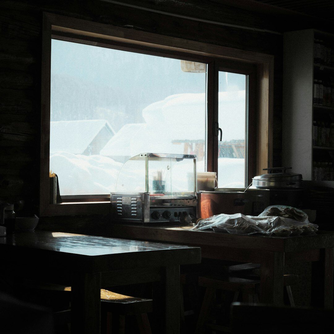 Bowl of hot winter soup with bread on a table near a window with snow outside