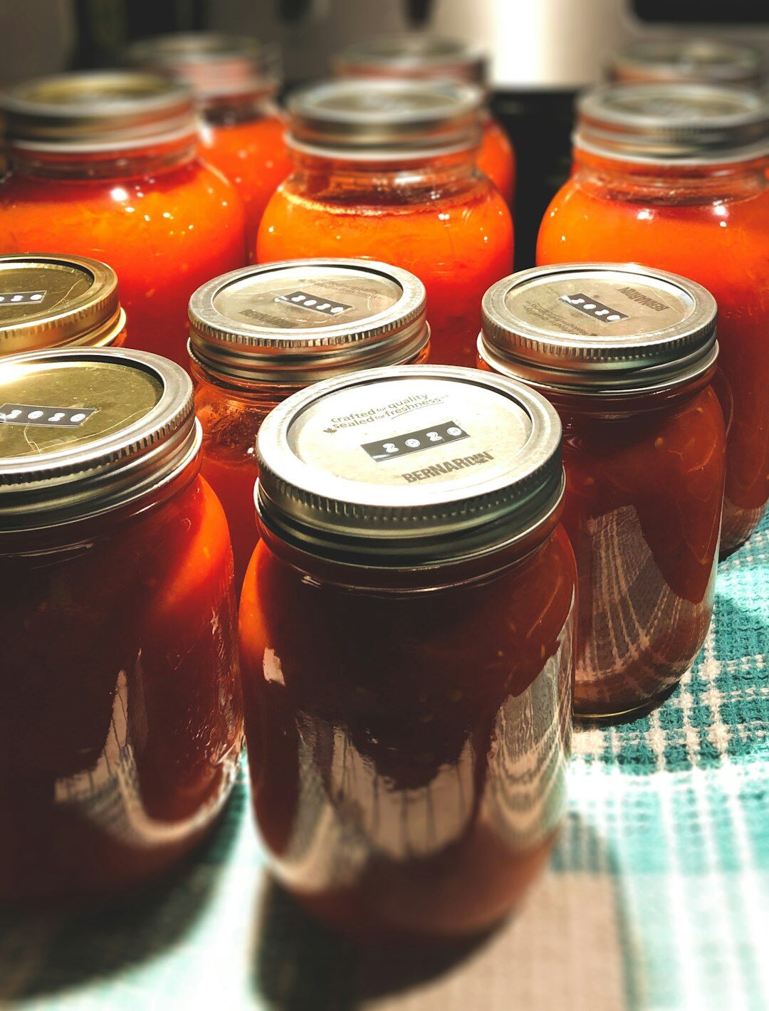 Rows of homemade preserved vegetables in glass jars on a pantry shelf